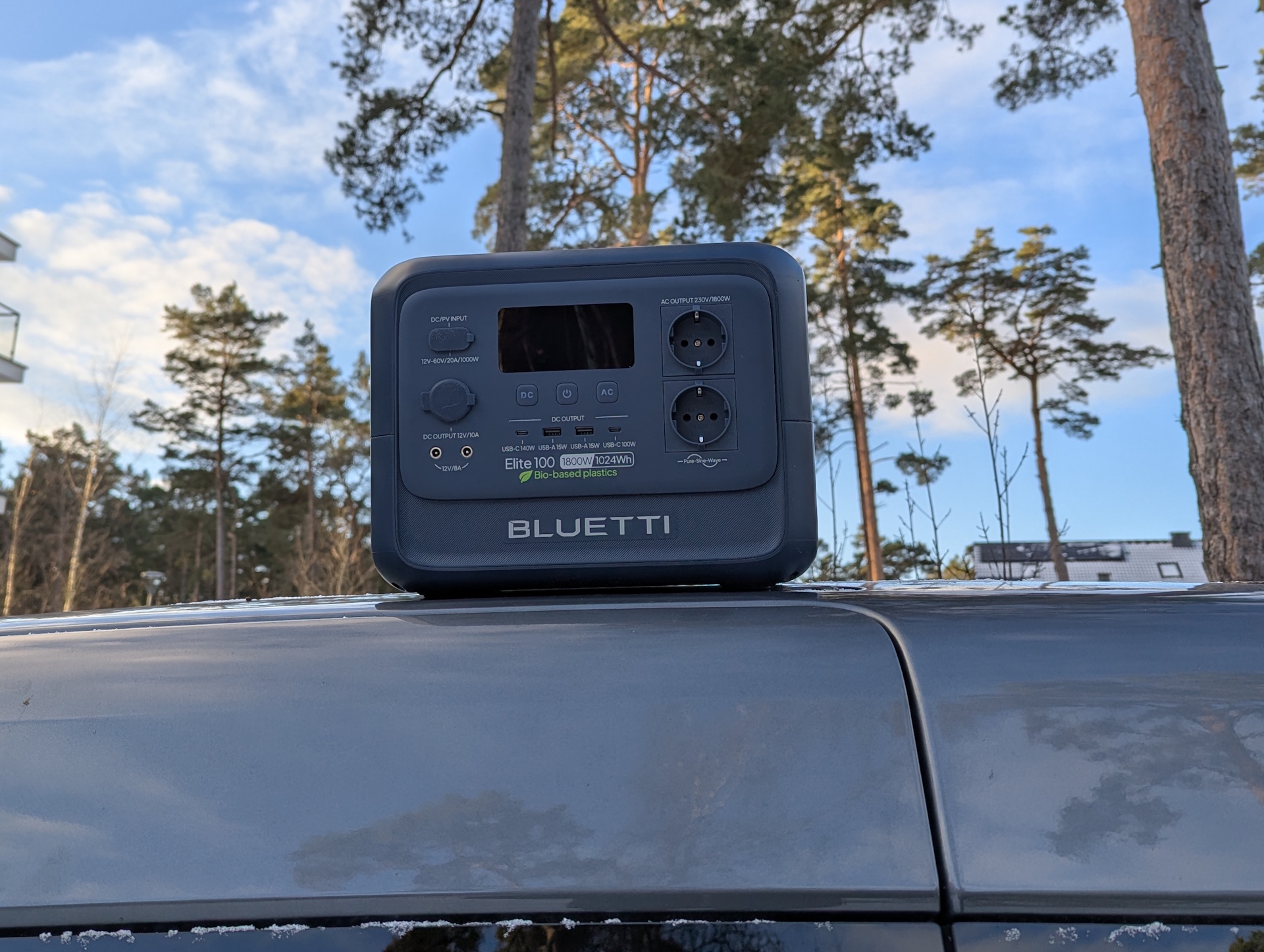 Bluetti Elite 100 V2 Bio-based on a car roof with pine trees in the background