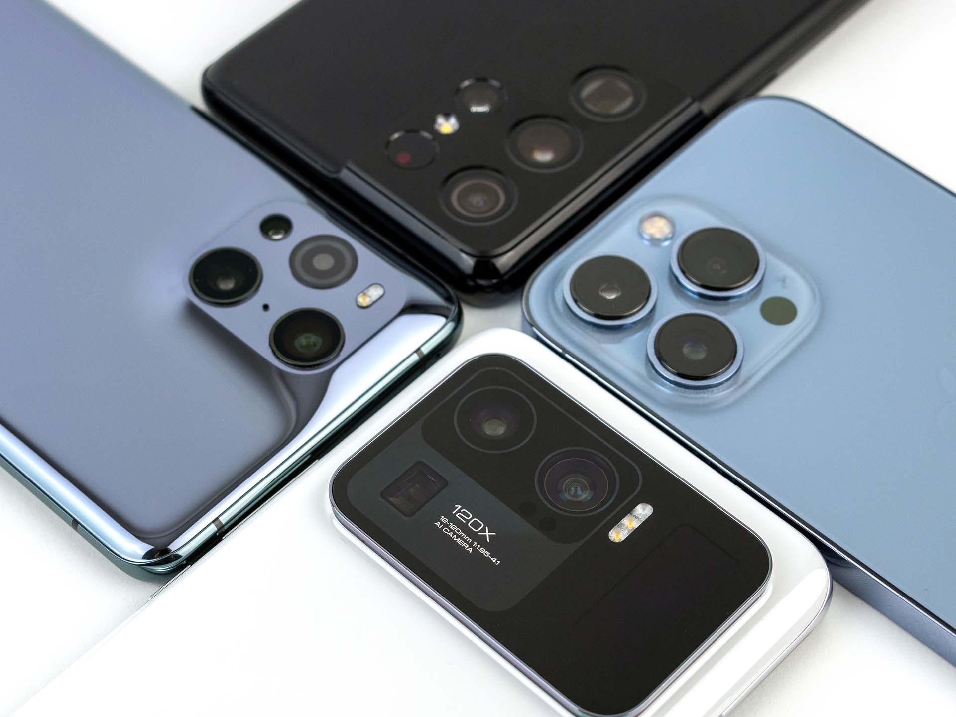  Four smartphones with camera stabilizers arranged on a white surface.
