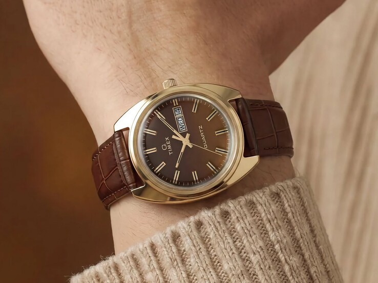 Timex Q 1976 Day and Date with a brown fumé dial and gold-tone case, shown on a wrist with a brown leather strap.