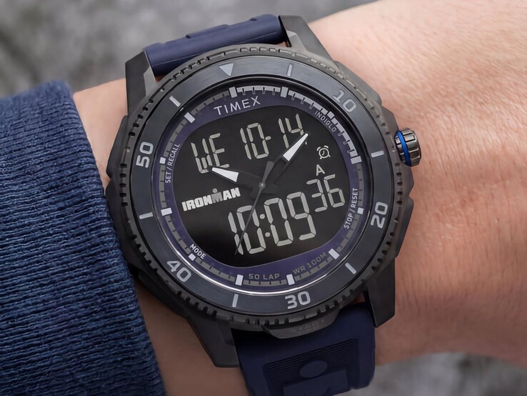 Black Timex Ironman Adrenaline ana-digi watch with a dark blue strap and blue crown accent, shown on a wrist.
