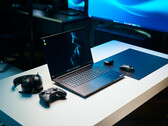 Razer Blade 18 2026 gaming laptop setup on a white desk with glowing RGB keyboard, mouse, gaming controller, and headphones in a dark studio setting.