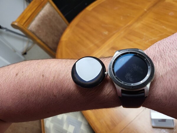 A strapless Pixel Watch crafted in a stainless steel finish joins the Galaxy Watch on its right atop a wrist for scale. (Image source: u/tagtech414 via reddit)
