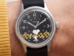 Close-up of the Timex MK1’s black dial showing Snoopy against a yellow-and-black checkered graphic with Arabic hour markers and luminous hands.