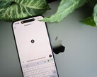 Smartphone with the ChatGPT app open, resting on a laptop next to plant leaves