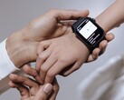 An adult hand setting up a smartwatch on a child’s wrist