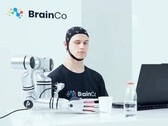 A user of BrainCo's mind-control technology robotically grabbing an apple by thought alone.