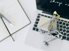 Miniature shopping cart on a laptop keyboard, with Shop now on the screen