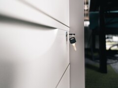 A key sitting in the lock of a closed wooden drawer