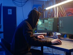 Generic hacker at a dual-monitor workstation executing a supply chain attack.
