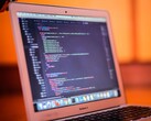 Open MacBook showing program code on its screen
