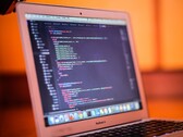 Open MacBook showing program code on its screen
