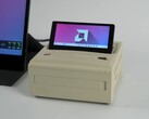 A retro-style Ayaneo AM01S mini PC in a beige finish, featuring a built-in flip-up secondary display showing the Windows desktop. (ETA Prime via YouTube)