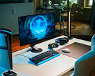 A clean studio gaming setup featuring the Sony Inzone M10S II monitor on a white desk alongside a vertical PlayStation 5 Pro console, mechanical keyboard, wireless mouse, and headset with subtle blue lighting.