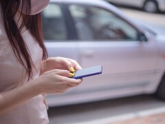 A woman typing on her smartphone with a silver car in the background