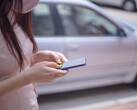 A woman typing on her smartphone with a silver car in the background