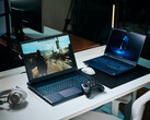 Two gaming laptops sitting on a white desk displaying detailed path-traced game footage next to a controller, mouse, and headset in a studio room.