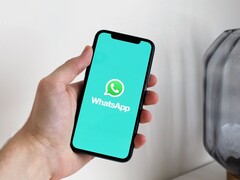 Hand holding a smartphone with the WhatsApp app open