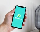 Hand holding a smartphone with the WhatsApp app open