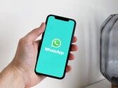 Hand holding a smartphone with the WhatsApp app open