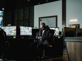 A security analyst in a control room in front of several monitors