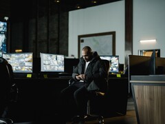 A security analyst in a control room in front of several monitors