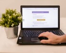 Laptop on a desk showing an open email inbox, with a potted plant beside it.