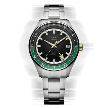 Timex Atelier GMT Première M1a with a black dial, green GMT ring, and stainless steel bracelet.