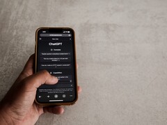 Hand holding a smartphone showing the ChatGPT interface above a gray stone surface