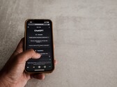Hand holding a smartphone showing the ChatGPT interface above a gray stone surface