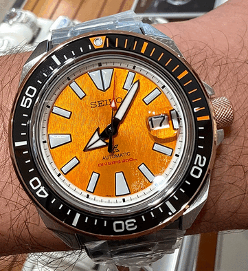 Close-up of the Seiko Prospex HBB005K1 showing its textured amber dial, oversized luminous hour markers, broad hands, date window, and black dive bezel with orange markings.