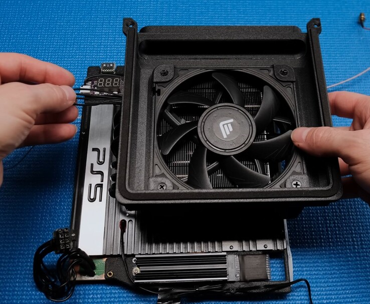 Close-up of the Tiny PS5 Redux cooling setup with a Noctua fan, 3D-printed shroud, and exposed PS5 motherboard. (Image source: Not From Concentrate via YouTube)