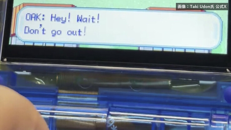 Close-up of the transparent-blue FPGBA SP handheld, showing its folding hinge and Pokémon dialogue on screen.