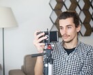 A young man films himself at home with a smartphone mounted on a tripod