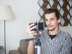 A young man films himself at home with a smartphone mounted on a tripod