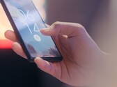 A hand holds a smartphone and unlocks it using the fingerprint sensor on the lock screen.