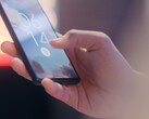 A hand holds a smartphone and unlocks it using the fingerprint sensor on the lock screen.