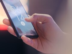 A hand holds a smartphone and unlocks it using the fingerprint sensor on the lock screen.