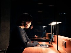 Woman working on a laptop in a dark office at night