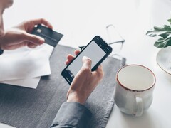 Person tapping on a smartphone while holding a bank card in the other hand