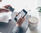 Person tapping on a smartphone while holding a bank card in the other hand