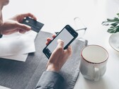 Person tapping on a smartphone while holding a bank card in the other hand