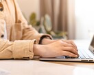 Hands typing on the keyboard of an open laptop at a bright desk