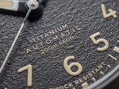 Close-up of the Timex Expedition Field Post Titanium’s textured black dial with Arabic numerals, luminous hands and markers, and date window.