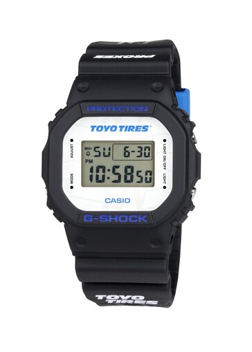 The white dial prominently features Toyo Tires branding, while blue lettering adds contrast to the classic square G-Shock design.