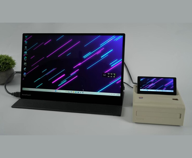 The Ayaneo AM01S mini PC connected to an external monitor, showing Windows on both the large display and the built-in flip-up secondary screen. (Image source: ETA Prime via YouTube)