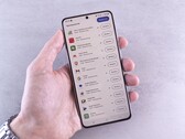 A hand holds a smartphone that shows a list of updates on screen.