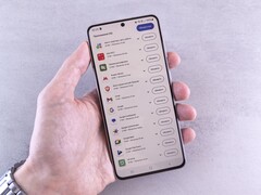 A hand holds a smartphone that shows a list of updates on screen.