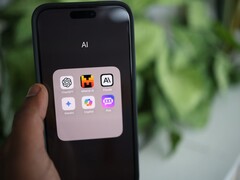 Hand holding a smartphone with a folder full of AI apps on the screen