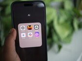 Hand holding a smartphone with a folder full of AI apps on the screen