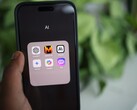 Hand holding a smartphone with a folder full of AI apps on the screen